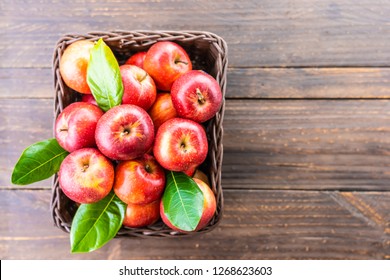 A lot of red apple fruit in brown basket on table