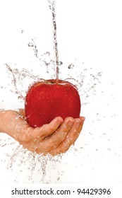 Red apple in hand under flowing water on a white background