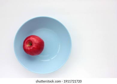 Red Apple On Blue Plate. Overhead View Of Fresh Ripe Fruit On White Table Background. Copy Space, Selective Focus