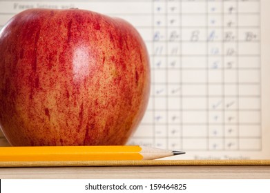Red Apple On A Book With Pencil And Vintage Report Card In Background