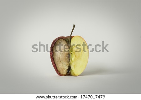 red apple with one half good and the other half rotten, concept of time, fruit that becomes garbage and that is thrown away, white background, isolated object