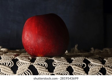 RED APPLE RESTING ON MACRAME MAT IN SIDELIGHT