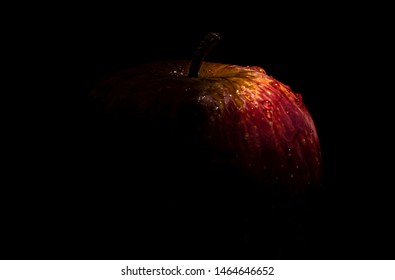 Red Apple sprinkled with water drops in dark setting with text space on left side