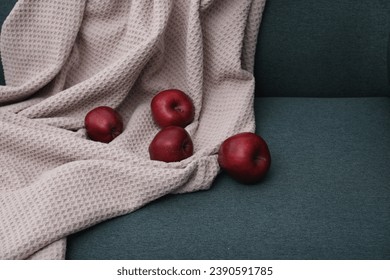 Red apples and beige blanket on green sofa - Powered by Shutterstock