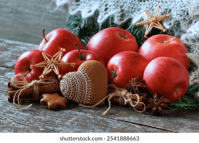 Red apples, cinnamon gingerbread heart, straw snowflakes and anise on a wooden table, fir branches and white shawl. Christmas background. - Powered by Shutterstock