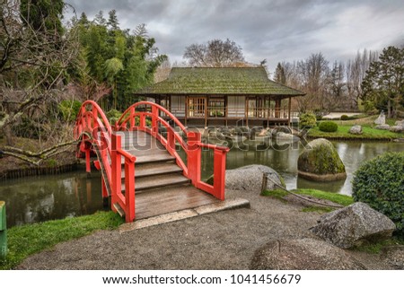 Red arch bridge in public japanese garden in Toulouse, France
