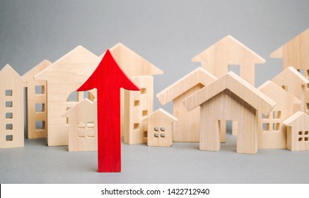 Red Arrow Up And Miniature Wooden Houses. The Concept Of Rising Property Prices. High Mortgage Rates. Expensive Rental Apartment. Growing Demand For Home Purchase. Population Growth In The City.