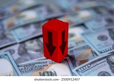 A red arrow pointing downwards on top of a pile of US dollar bills. Economic recession, financial decline, economic downturn concept.