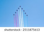 The red arrows performing maneuvers over blue sky in england, airplane jet performing air acrobatic and flying formations on an airshow in cosford united kindom