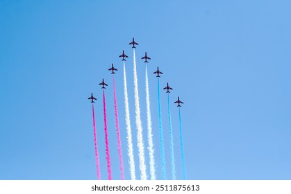 The red arrows performing maneuvers over blue sky in england, airplane jet performing air acrobatic and flying formations on an airshow in cosford united kindom - Powered by Shutterstock