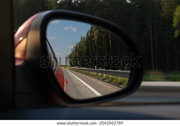 Red automobile mirror, the road is\
reflected in the long-distance mirror of the\
car