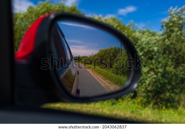 Red automobile mirror, the road is\
reflected in the long-distance mirror of the\
car