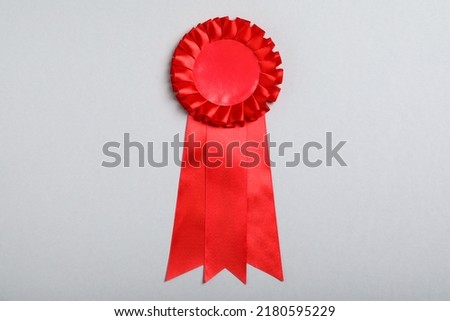 Red award ribbon on grey background, top view