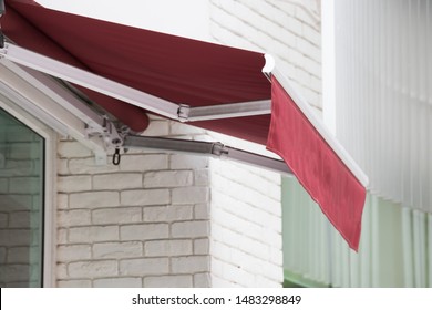 Red Awning Over Window Of Shop.