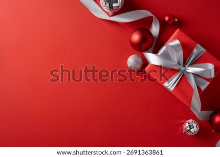 A red background features a wrapped gift with a silver bow, complemented by shiny ornaments. Ideal for Christmas and New Year visuals, festive decor, gift ideas, and holiday greetings