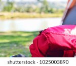 red backpack on floor close tent at campsite with blurry nature background no people, popular bag design for backpacker, lightweight, modern functionality style for camping trips holiday idea