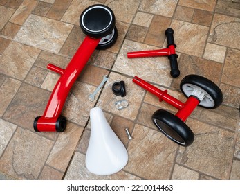 Red Balance Bike Parts Lying On The Ground Ready To Assemble.