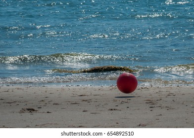 Red ball bouncing on the beach on a sunny summer day at the ocean