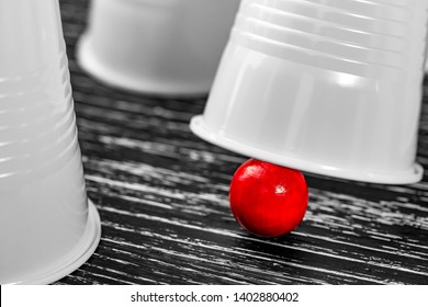 Red Ball Win Under A White Cup In The Game Of Cups. Black Old Wooden Table. The Concept Of The Right Choice In The Game And Life