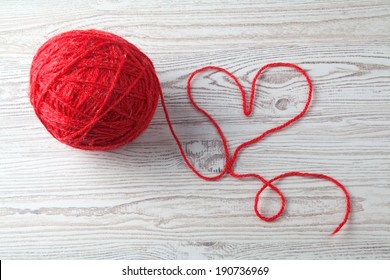 Red Ball Of Wool On Wooden Table Background