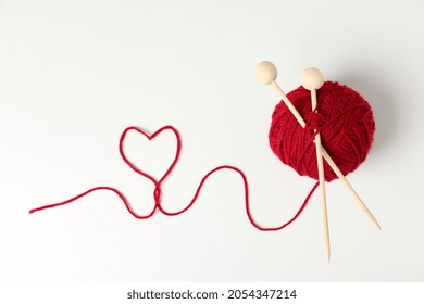 Red Ball Of Yarn And Knitting Needles On White Background