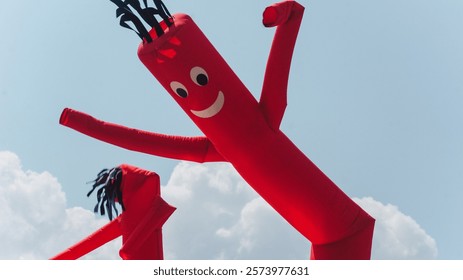 Red balloon men waving in the air against the blue cloudy sky in the daylight at the state fair.