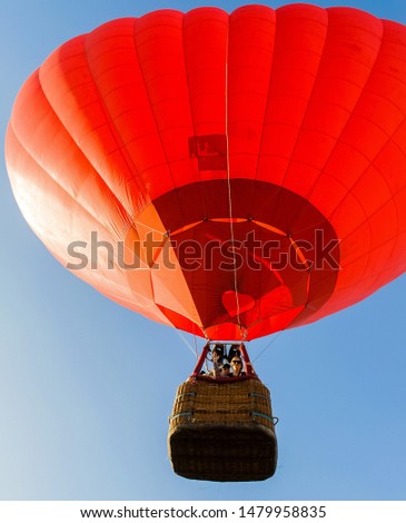 red balloon in the sky from the basket which looks out happy young couple -guy with a girl