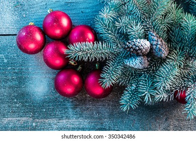 Red Balls In The Snow With A Christmas Tree And Pine Cones On A Table