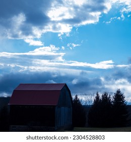 A red barn with cloudy a backdrop.