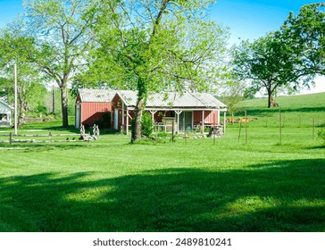 Red barn farmhouse on large acre lot farmland in Mansfield Missouri, grassy lawn and lush greenery trees, scenic peaceful agriculture town at agro-town agglomeration rural environment farmstead. USA - Powered by Shutterstock