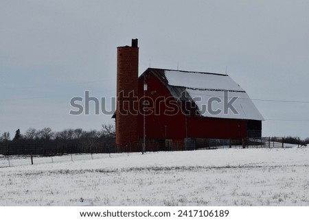Red barn and silo in a snowy farm field