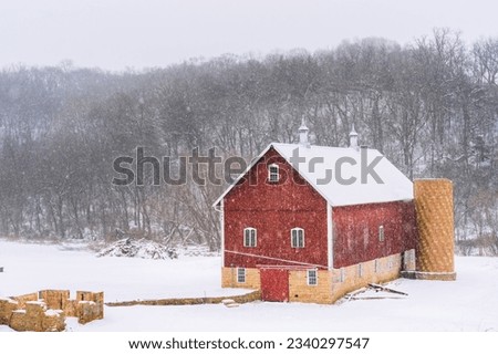 Red barn in snow with deciduous trees in background
