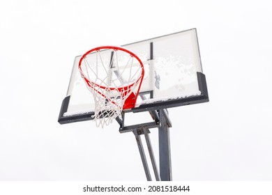 Red Basketball Hoop On A Backboard On A Light Background, Bottom View. Sports Equipment For A Team Outdoor Ball Game. Steel Frame, Plexiglass Shield.