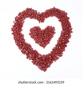 Red beans arranged in the shape of a heart on a white background, top view.