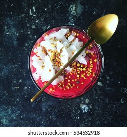 Red Beet Root Smoothie With Fruit, Coconut Flakes And Bee Pollen And Super Foods With Golden Spoon On Dark Background