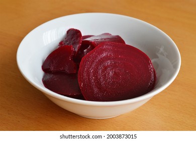 Red beet salad in bowl on wooden background