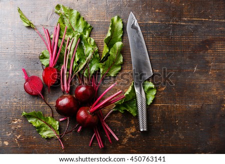 Red Beetroot with herbage green leaves and kitchen knife on wooden background