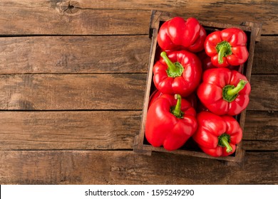 Red bell pepper in box on vintage wooden table with copyspace. Top view