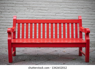 A Red bench and a brick wall