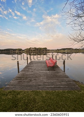 Red bench on the shore of a lake at sunset time