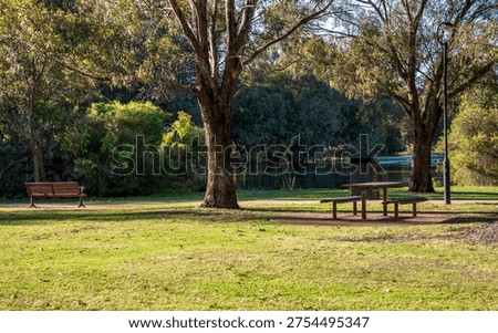 Red bench in shade under eucalypts overlooking small pond in Neil McDougall Park, Como suburb, Perth, Australia, 25 November 2021