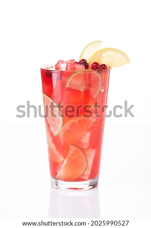 Red berry and fruit lemonade with lime and lemon slices and cranberry, ice cubes and appetizing foam in a tall glass on a white background