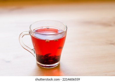 Red Berry Tea In A Transparent Cup On The Background Of A Wooden Table In A Cafe