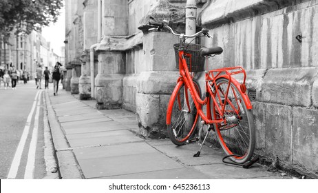 Red Bicycle on the Street, Isolated red color on black and white background, shallow depth of field, blurred walking people, captured in York England