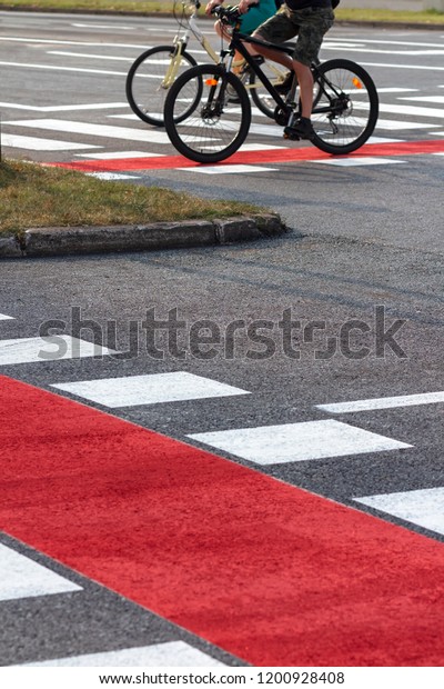 Red bike lanes and pedestrian crossing with\
two cyclists in the\
background