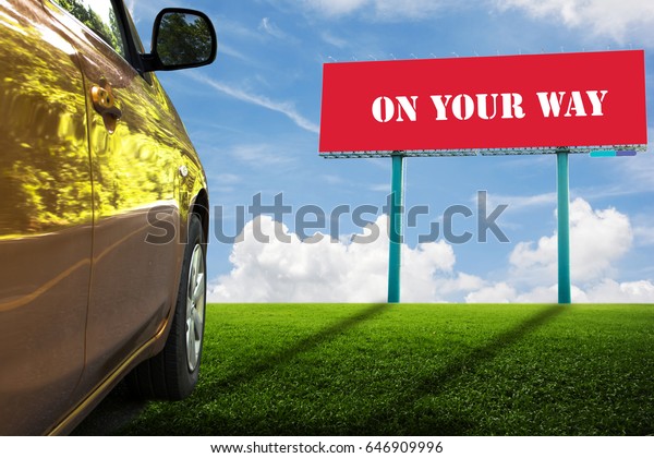 Red\
billboards on green field and Orange car. ON YOUR\
WAY