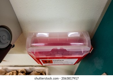 Red Biohazard Sharps Waste Container Mounted To The Wall Of A Public Restroom