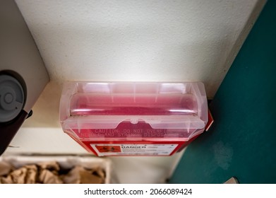 Red Biohazard Sharps Waste Container Mounted To The Wall Of A Public Restroom