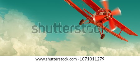 Red biplane flying in the cloudy sky. Retro style