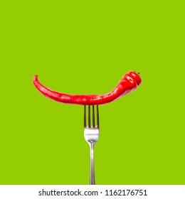 Red Bitter Chili Pepper On The Fork On Green Isolated Background. Creative Food Concept.